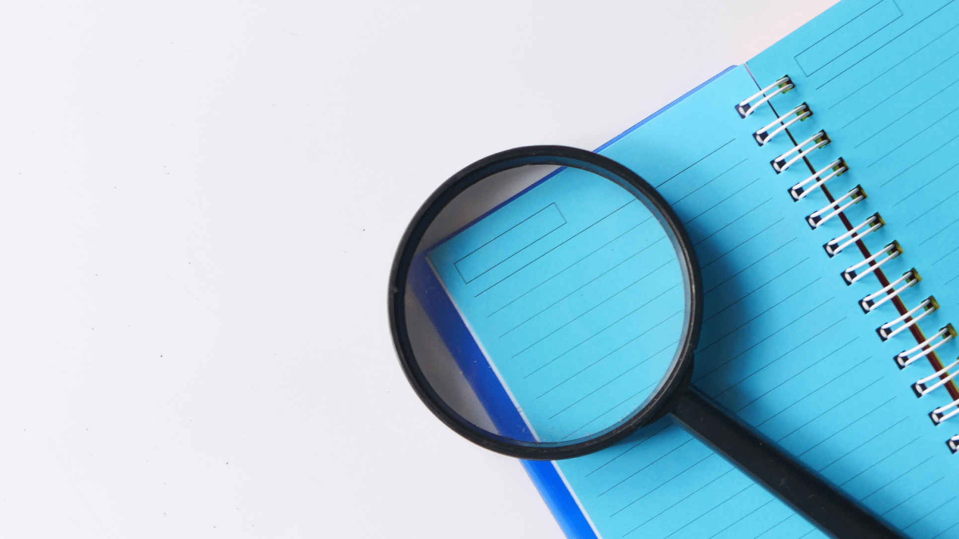 Magnifying glass on blue notepad, digital content audit