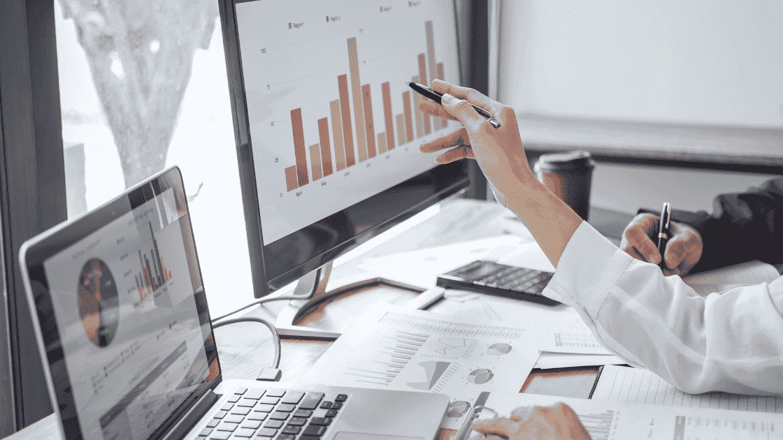 Office worker with laptop and computer pointing at computer screen