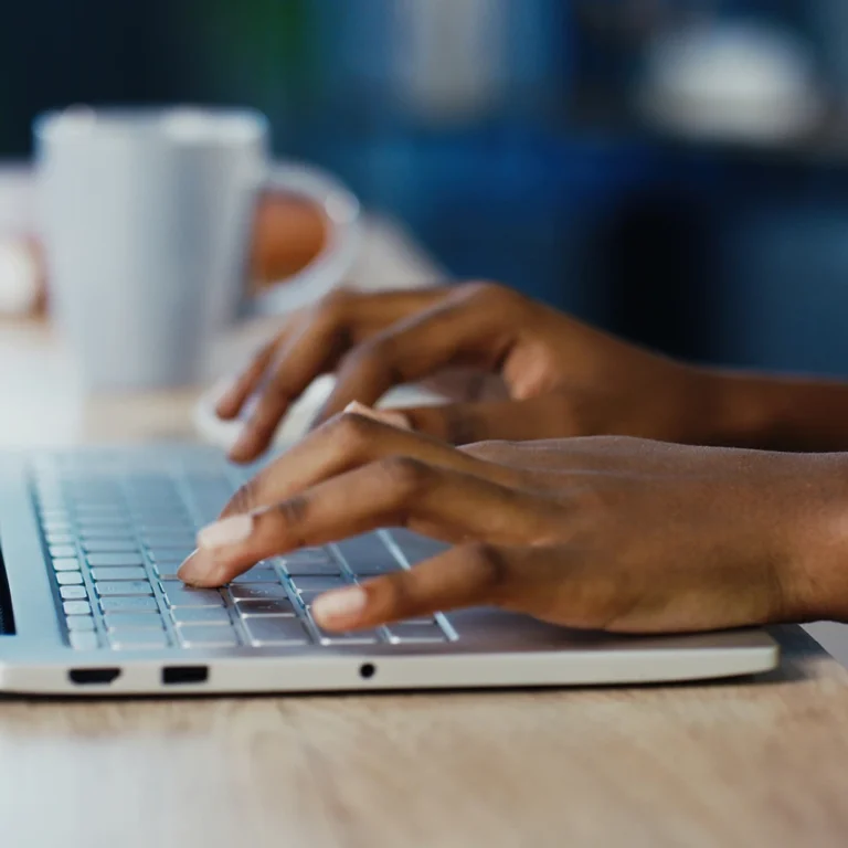 A woman focused on typing on a laptop, with her hands on the keyboard.
