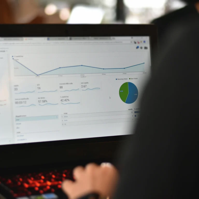 A person working on a laptop displaying a colorful graph, focused on data analysis or presentation.