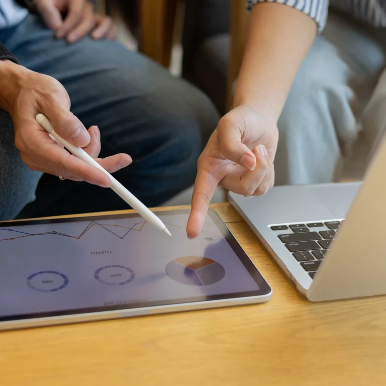 Two people analysing graphs on a tablet, engaged in discussion about the data displayed.
