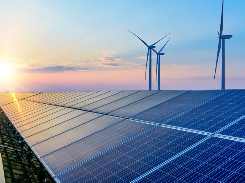 Solar panels and wind turbines silhouetted against a vibrant sunset sky, highlighting renewable energy sources.