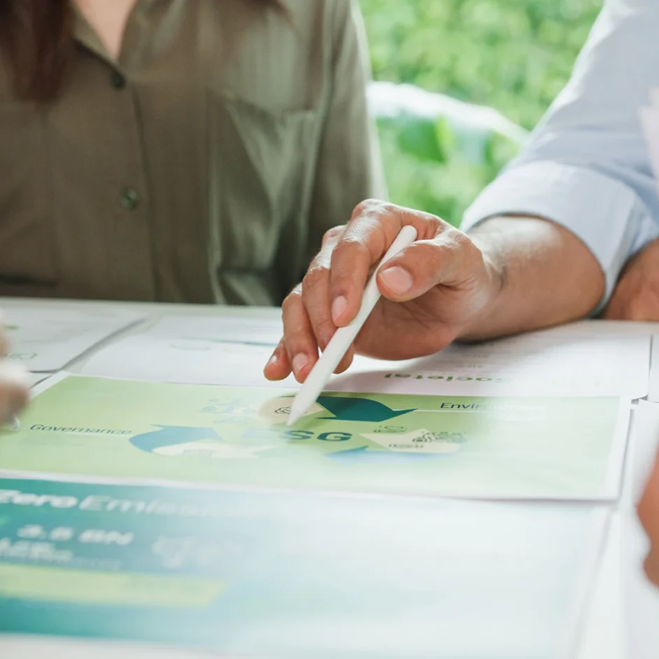 People gathered around a table, reviewing papers and writing with a pen.