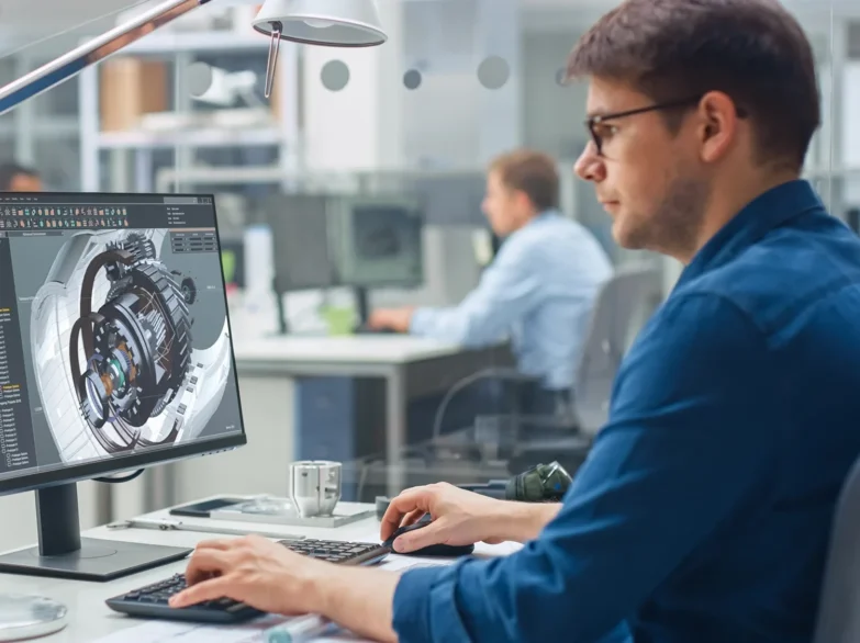 A man focused on his computer while working in a modern office environment.