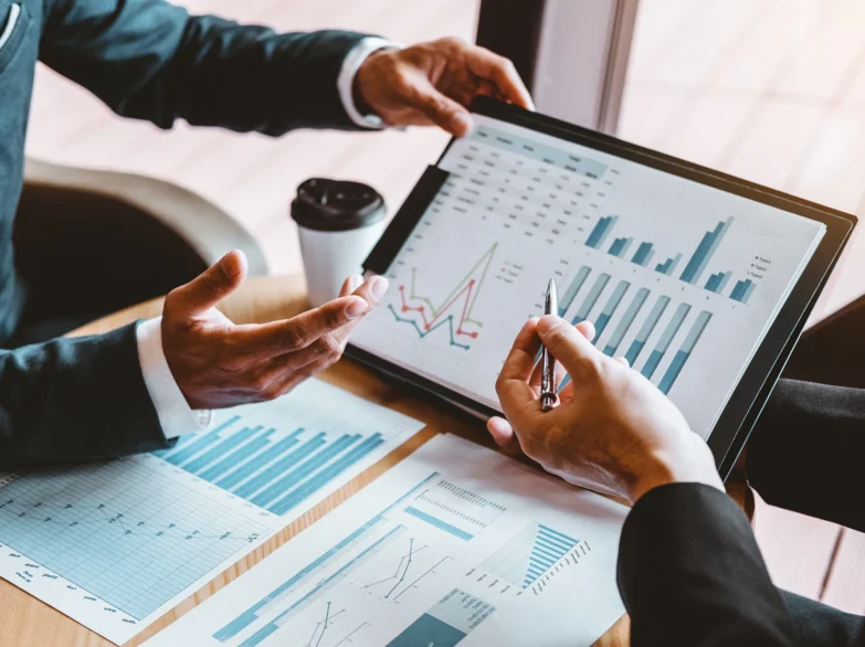 Business professionals collaborating on strategy and financial data using a tablet in a modern office setting.