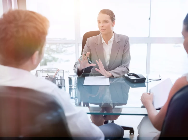 A woman in a business suit engages in conversation with two clients.