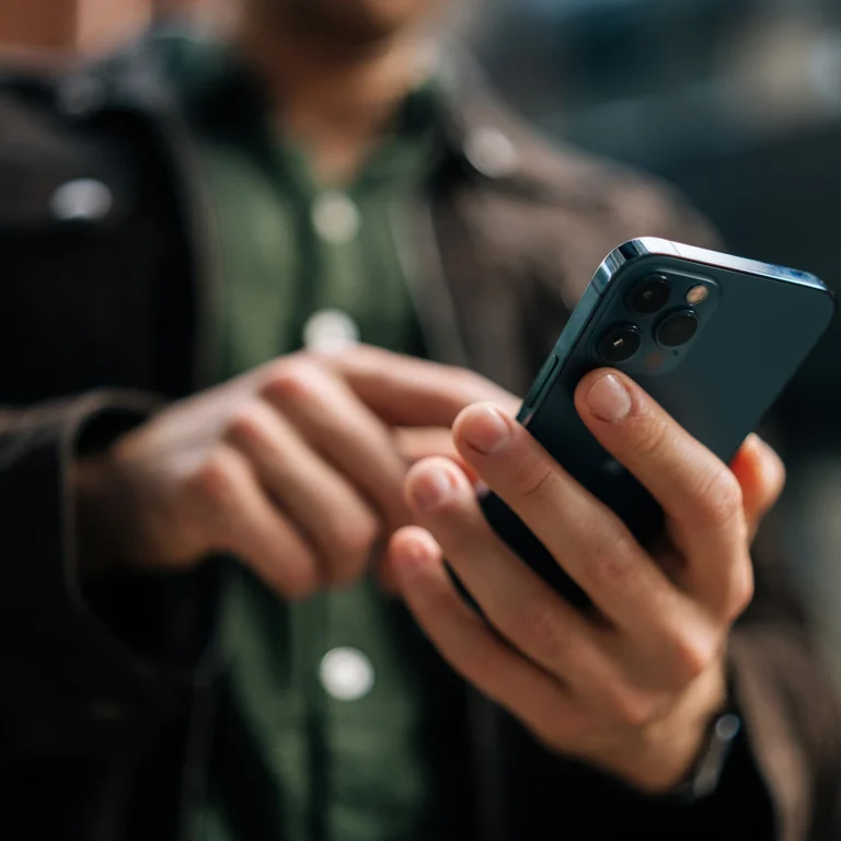 A man holding a cell phone in his hand, looking at the screen.
