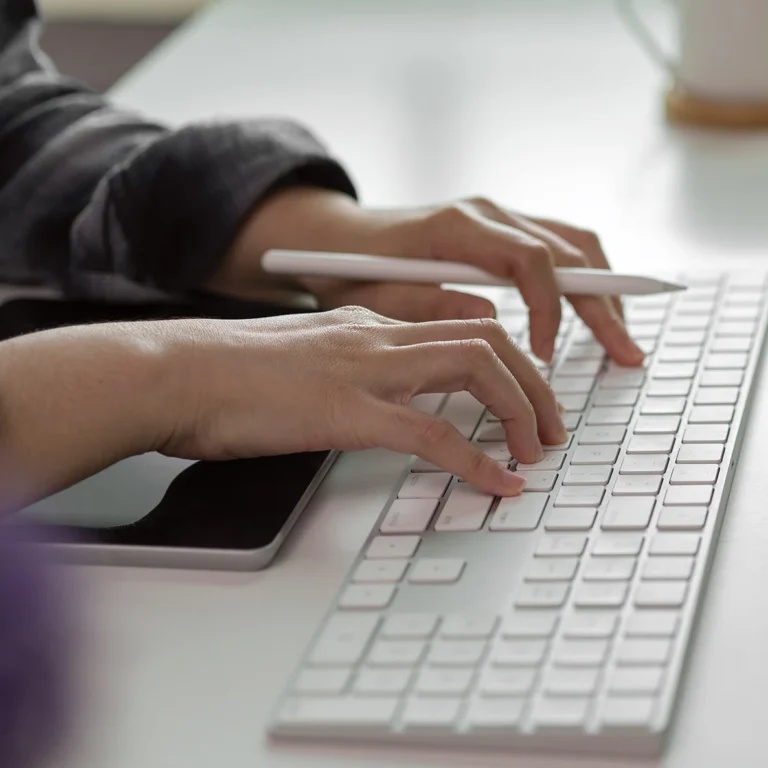A person focused on typing on a computer keyboard, with hands positioned over the keys.