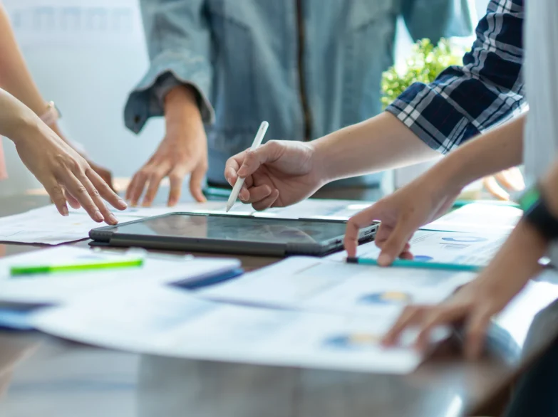 Business team collaborating on a tablet, discussing ideas and strategies in a modern office setting.