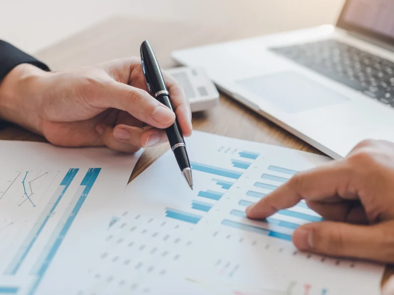 Two people collaborate on a business document using a pen and a laptop, focused on their work together.