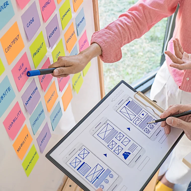 Two people collaborating at a whiteboard covered in colorful sticky notes, brainstorming ideas together.