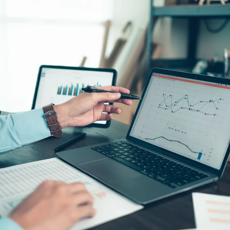 Businessman focused on laptop screen, analysing data with charts and graphs in a modern office setting.