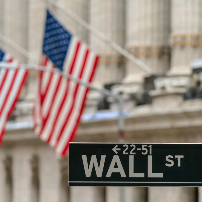 Wall Street sign with American flags in the background, New York City.