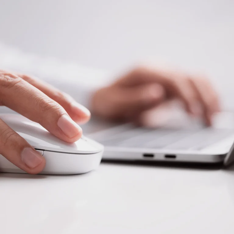 A person using a mouse while working on a laptop, focused on the screen and engaged in their task.