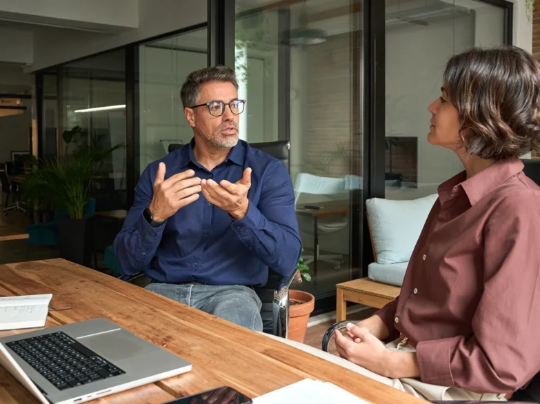 A man and woman engaged in conversation while sitting at a table.
