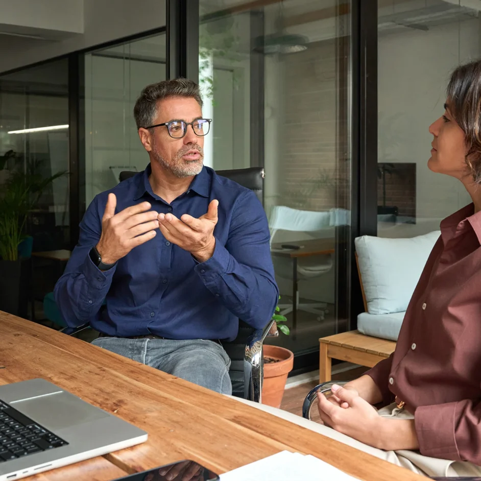 A man and woman engaged in conversation while sitting at a table.